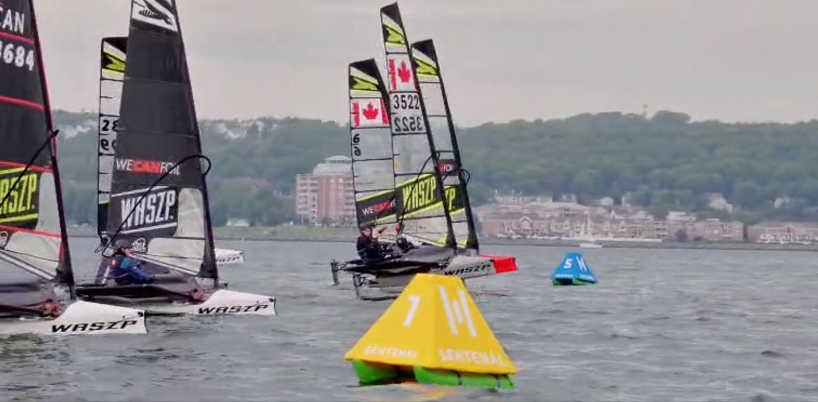 Foiling dinghies racing past two Sentenals holding position